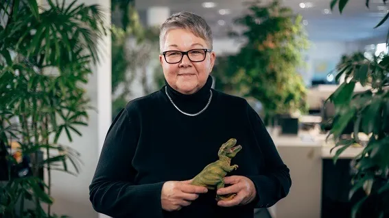 Kerstin standing in the office holding a dinosaur figurine