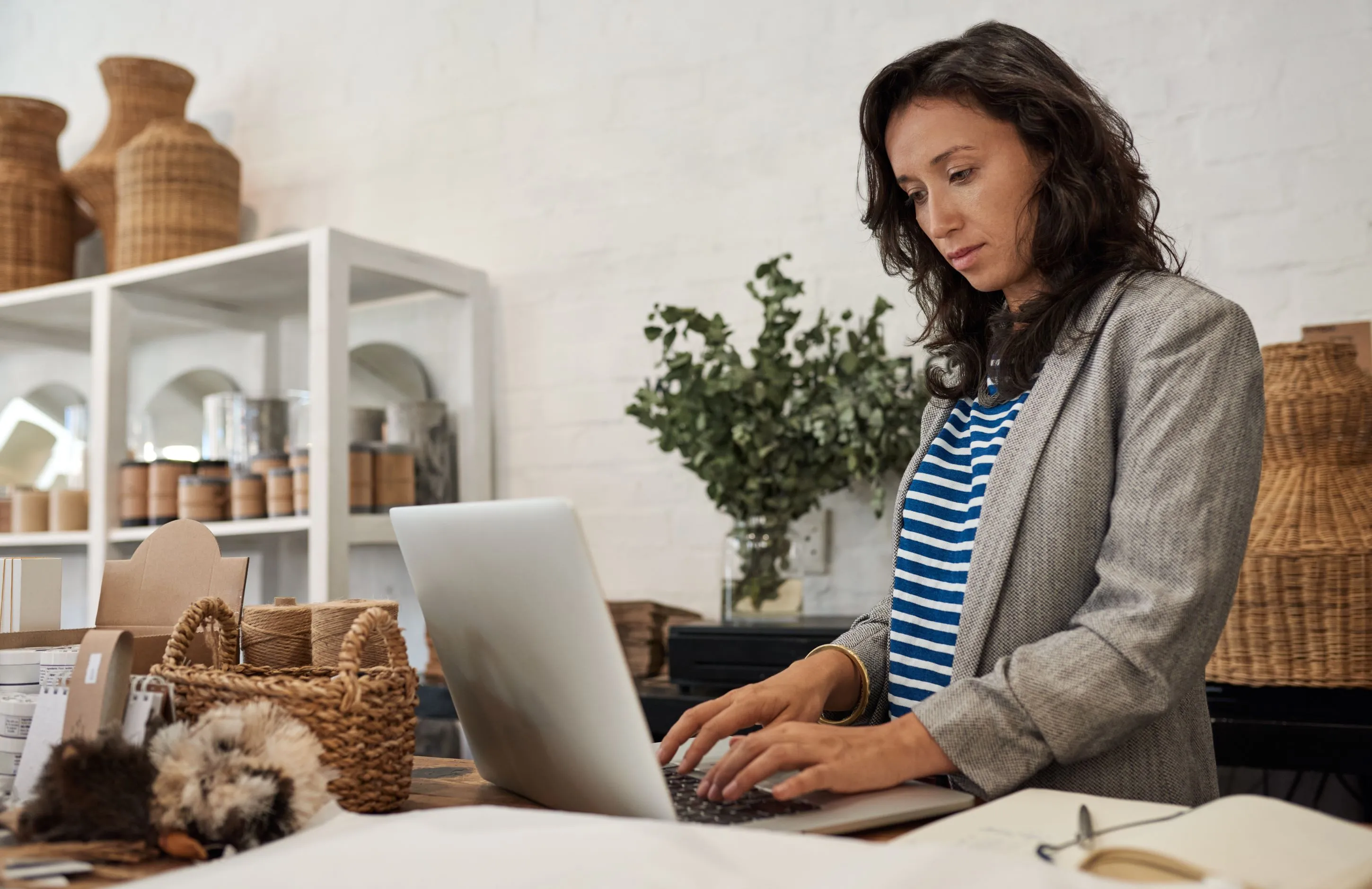 Women typing on her laptop in a shop with bast baskets