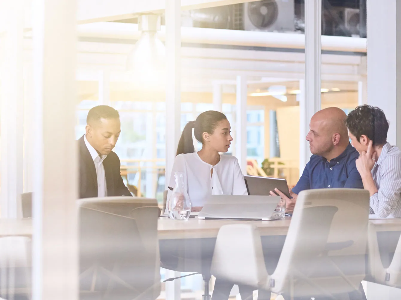 4 people talking in a meeting, office setting