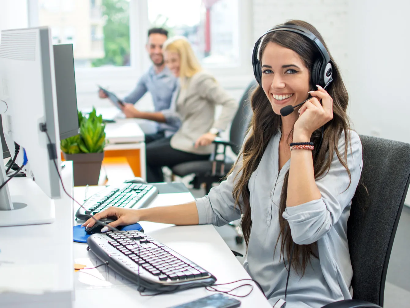 Woman talking on headphones in an office, smiling