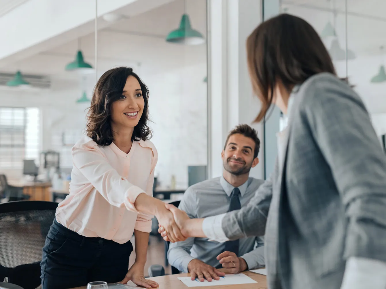 women shaking hands in an office while sealing a deal