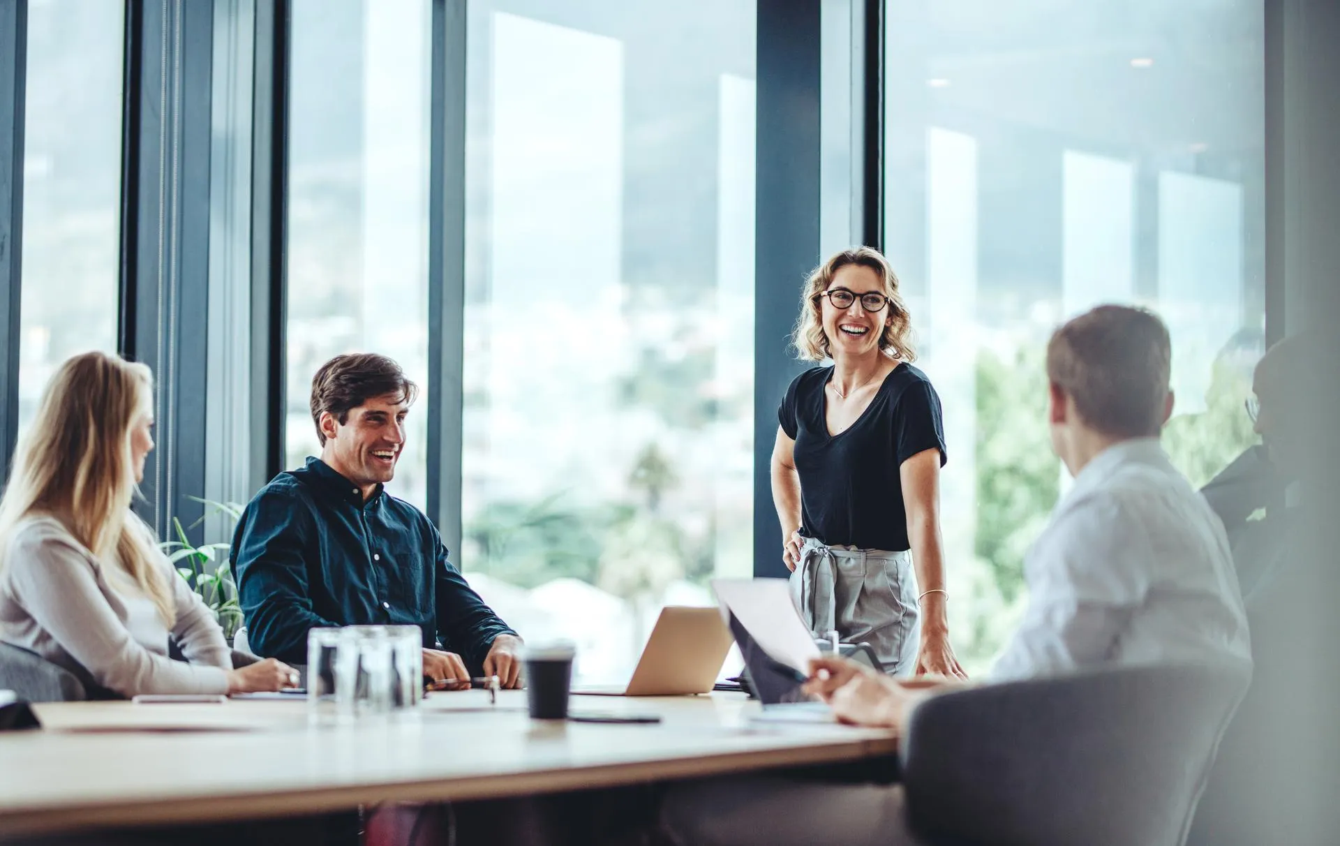 5 people laughing during an office meeting