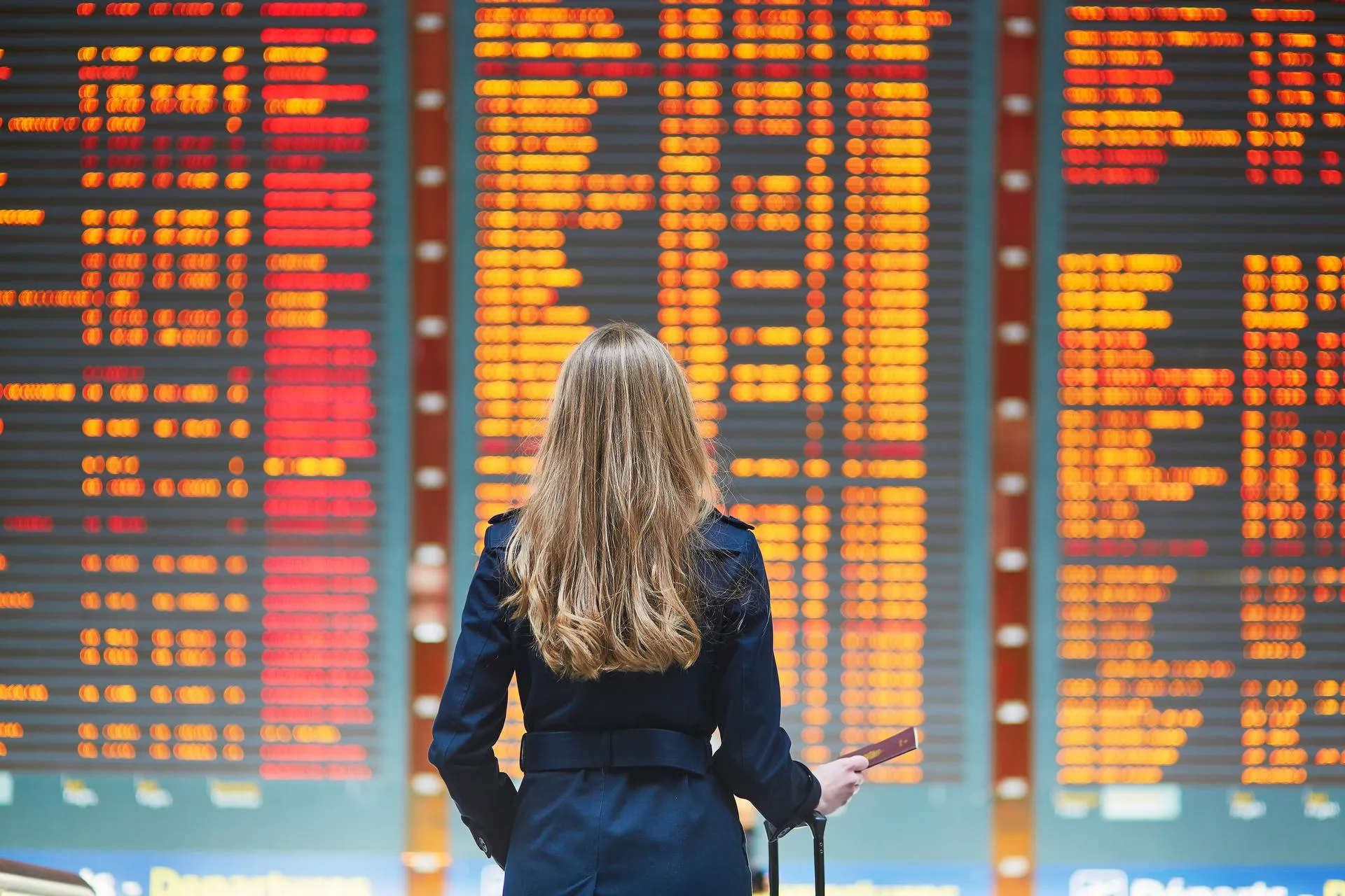 Woman standing in front of a big screen with flight arrivals/departures information