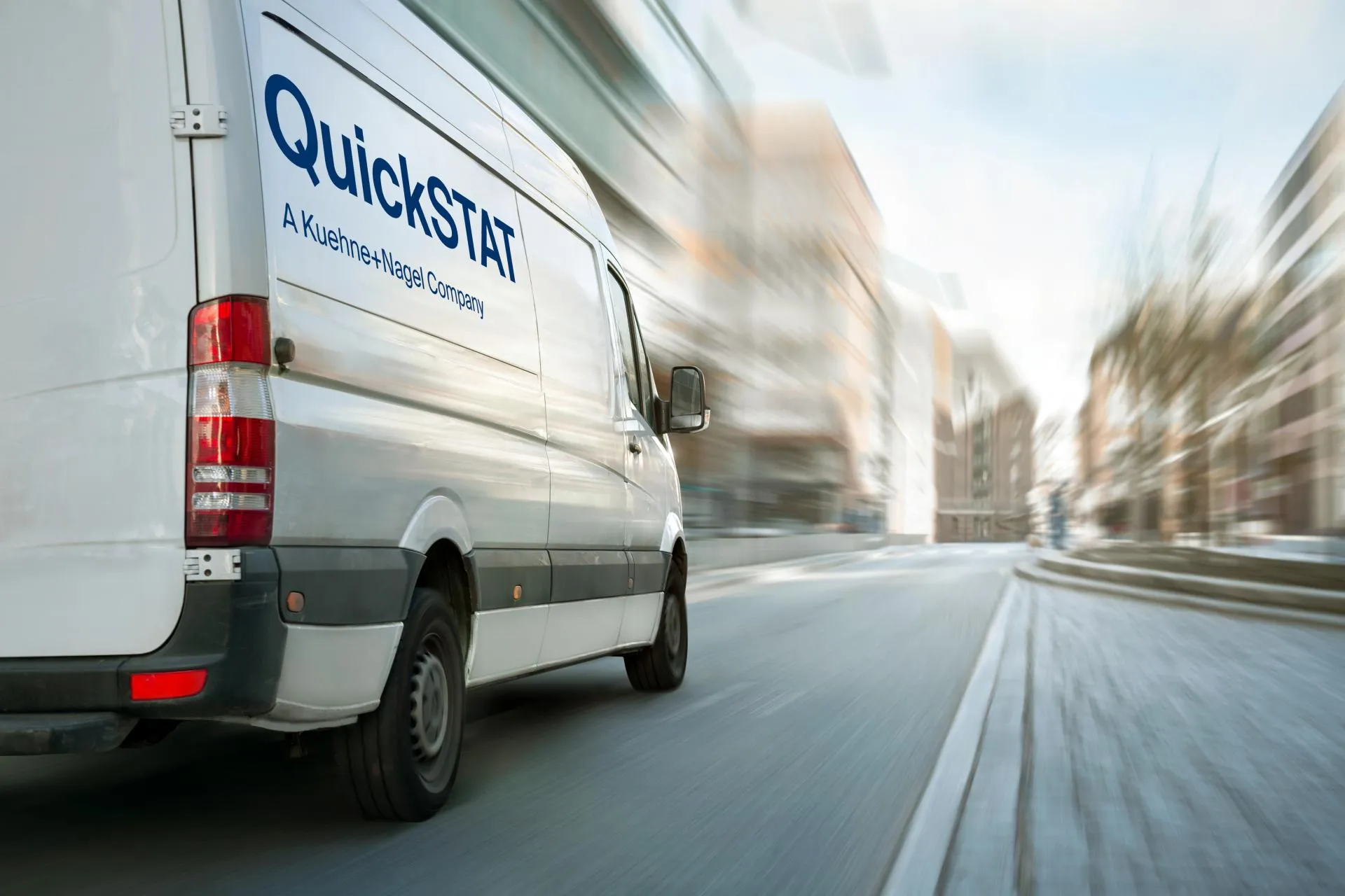 White van with QuickSTAT logo on the right side of the van, background is blurred, like its moving full speed.