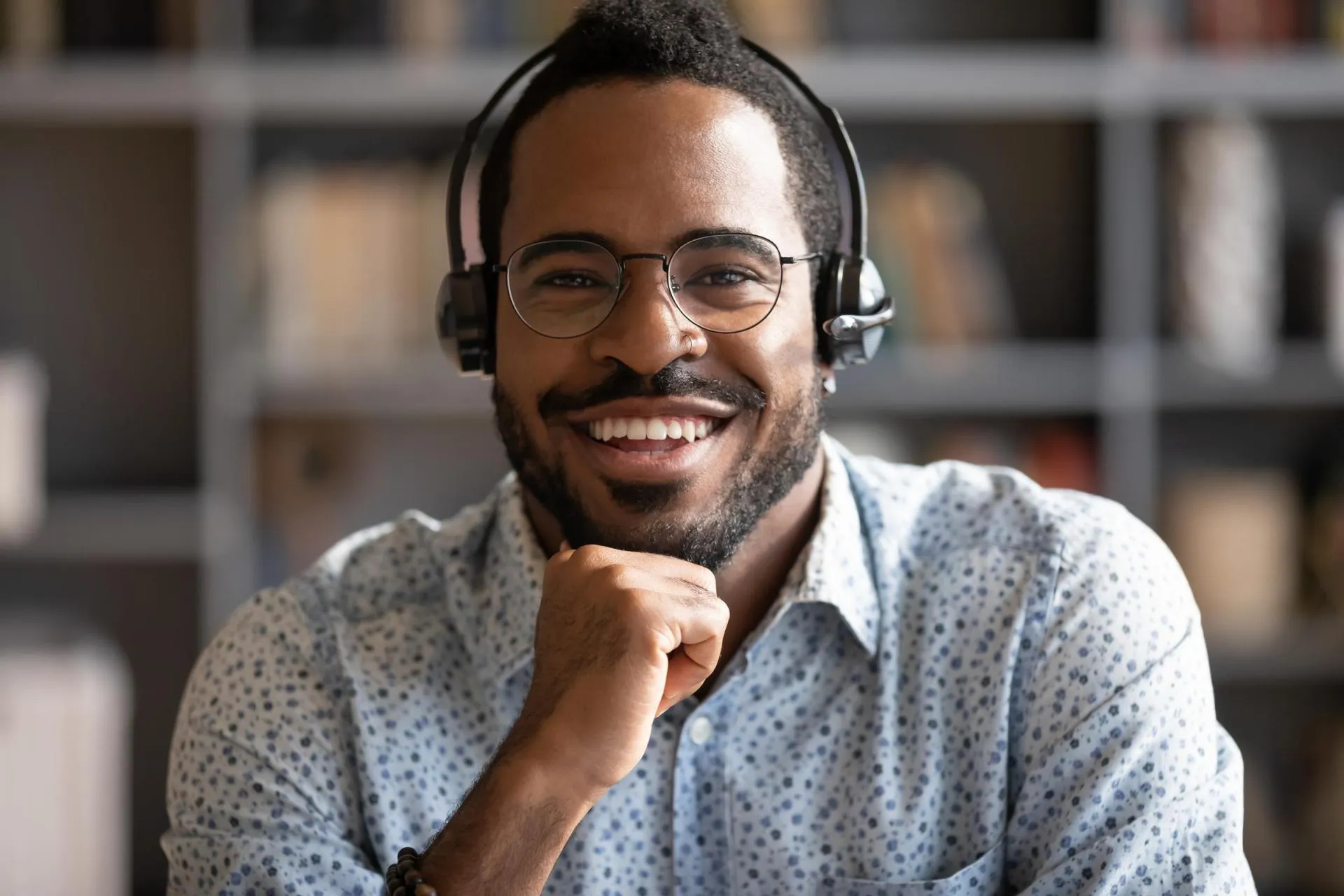 An African-American man is wearing headphones, ready to help customers at the call center.