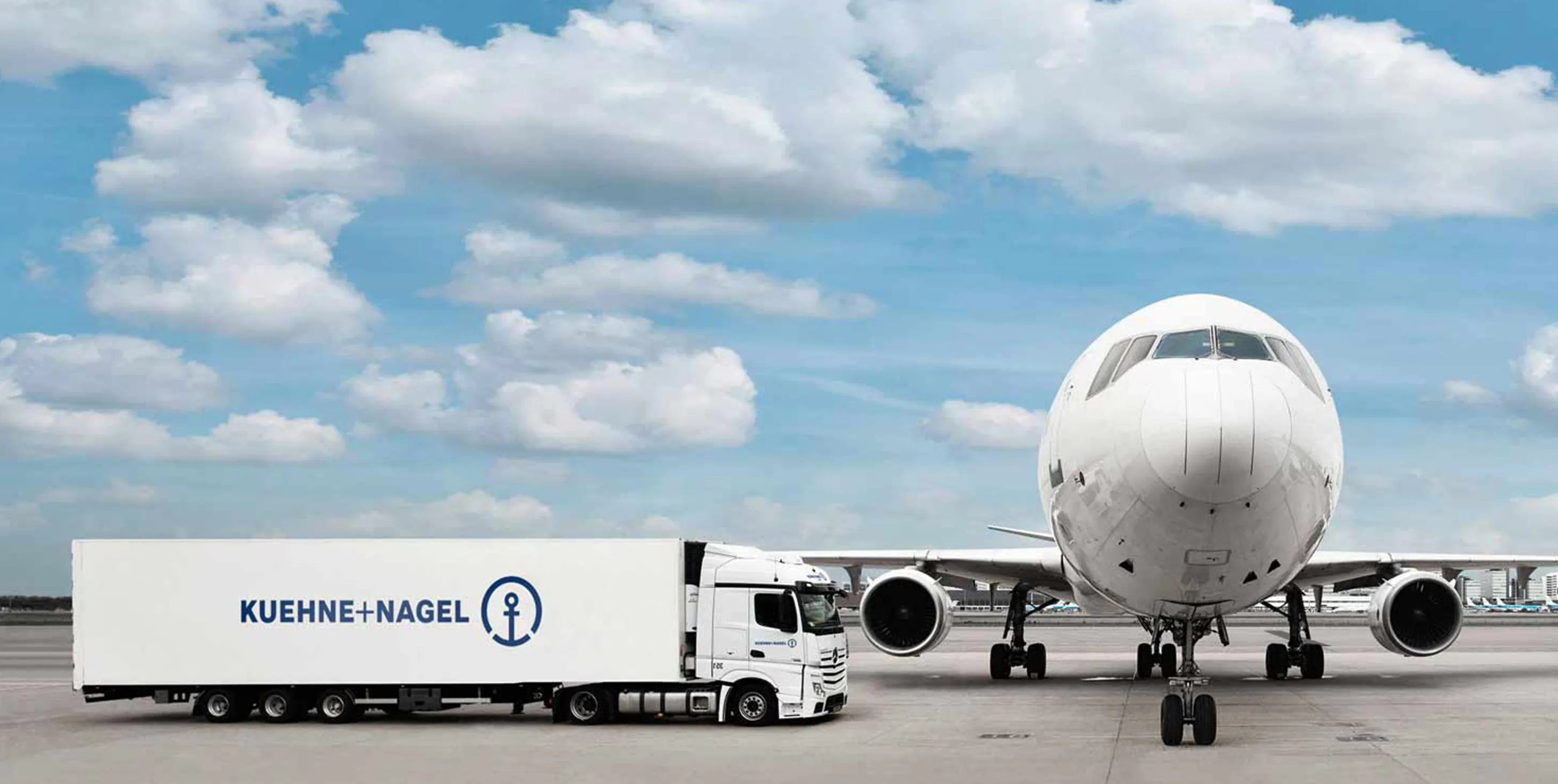 White Kuehne Nagel truck next to a plane