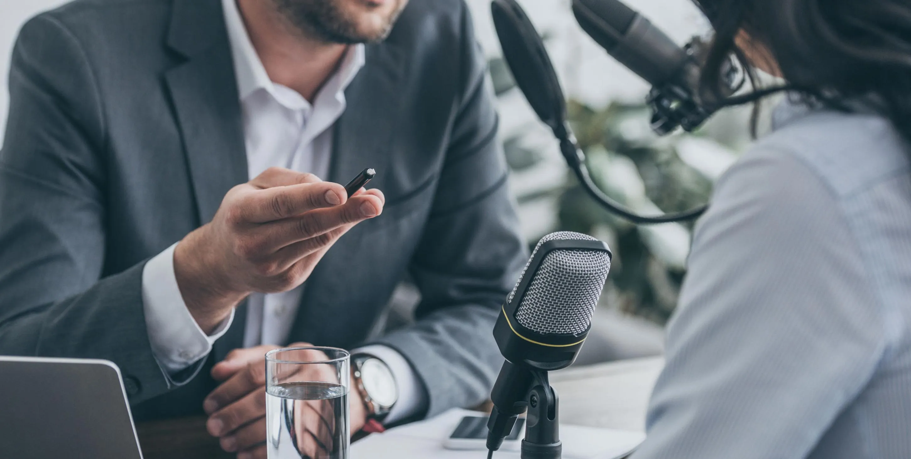 Man and woman speaking into podcast microphone