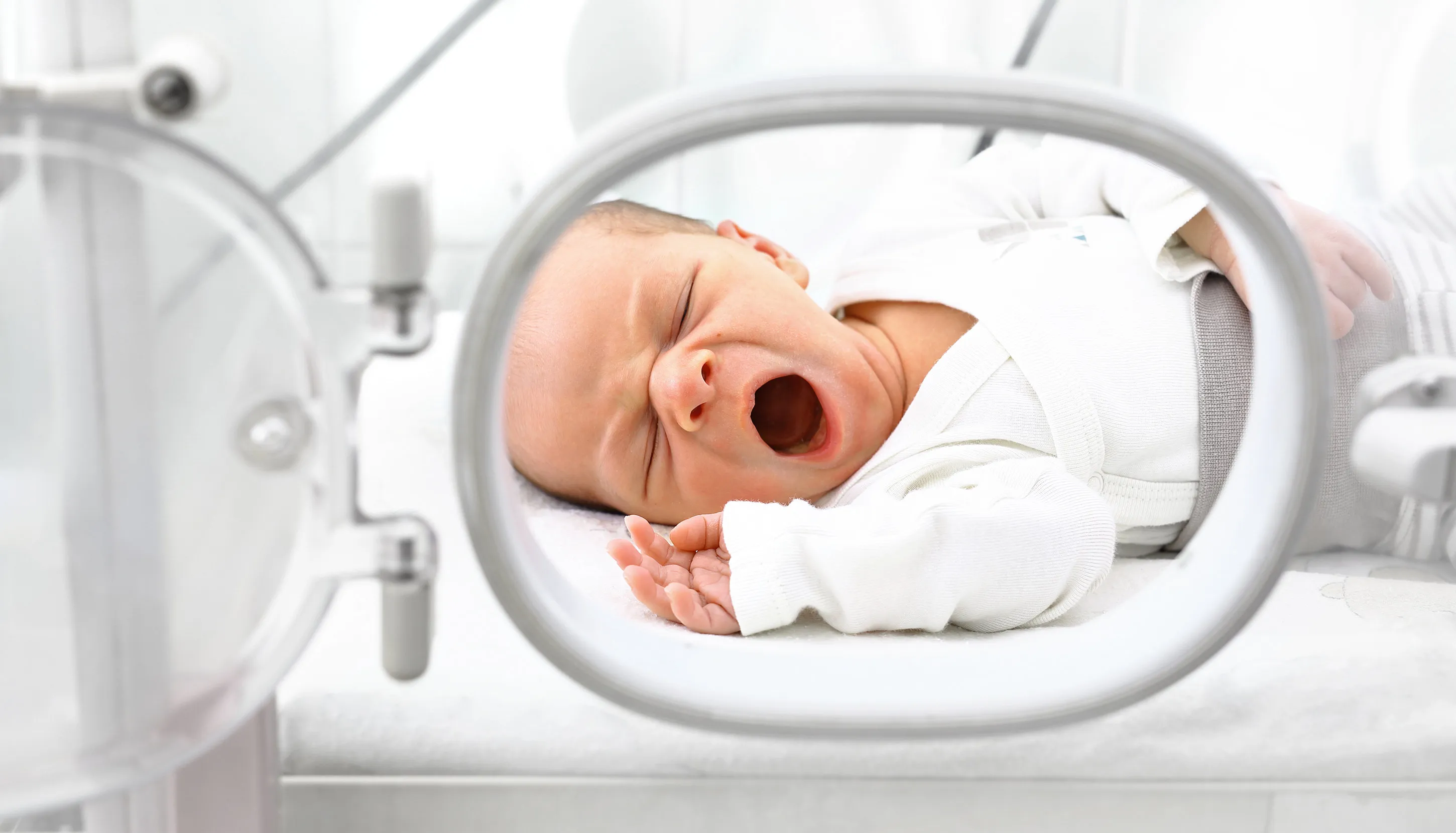 A baby yawning lazying in an incubator