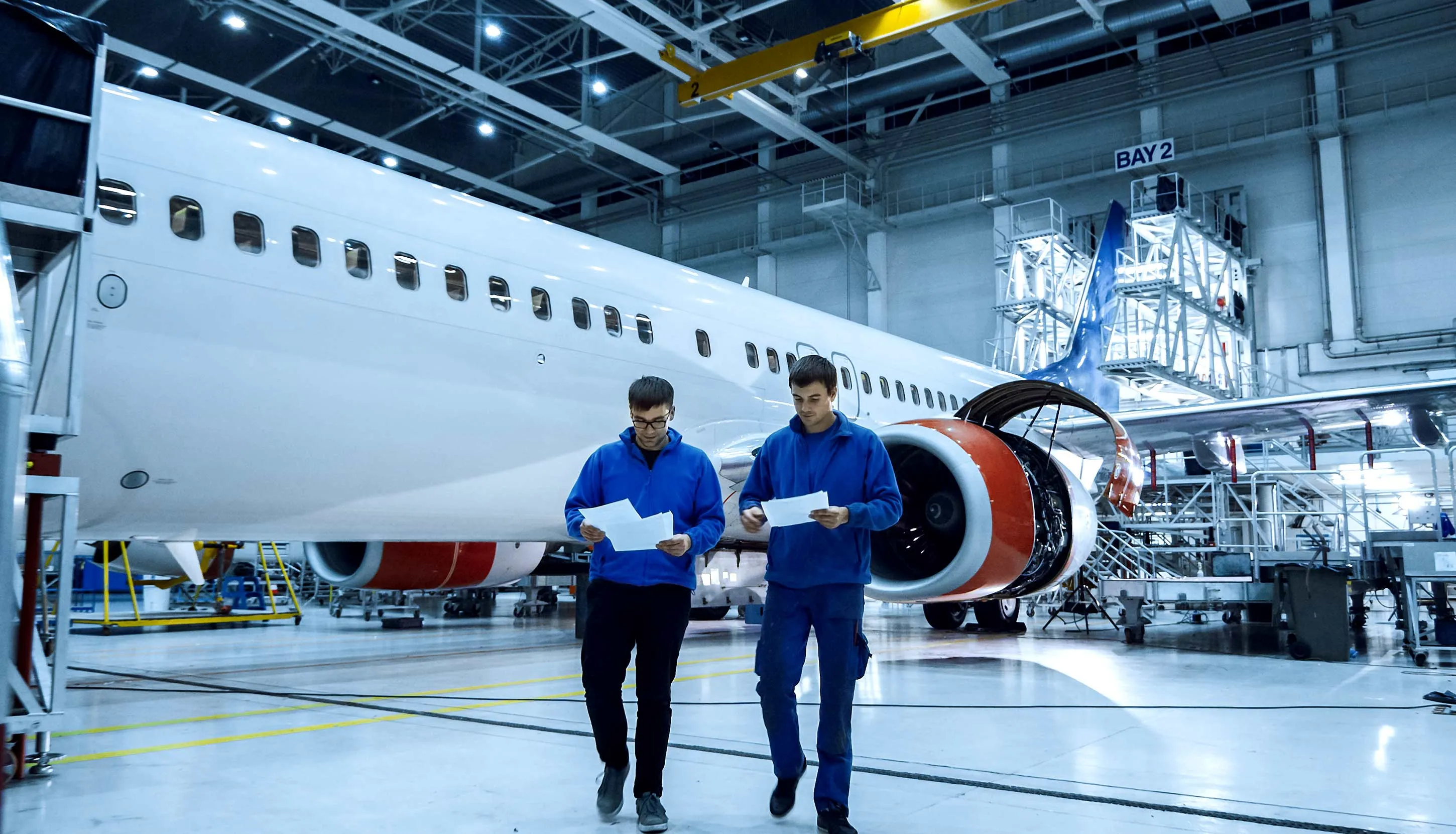 People talking next to the big plane inside the hangar