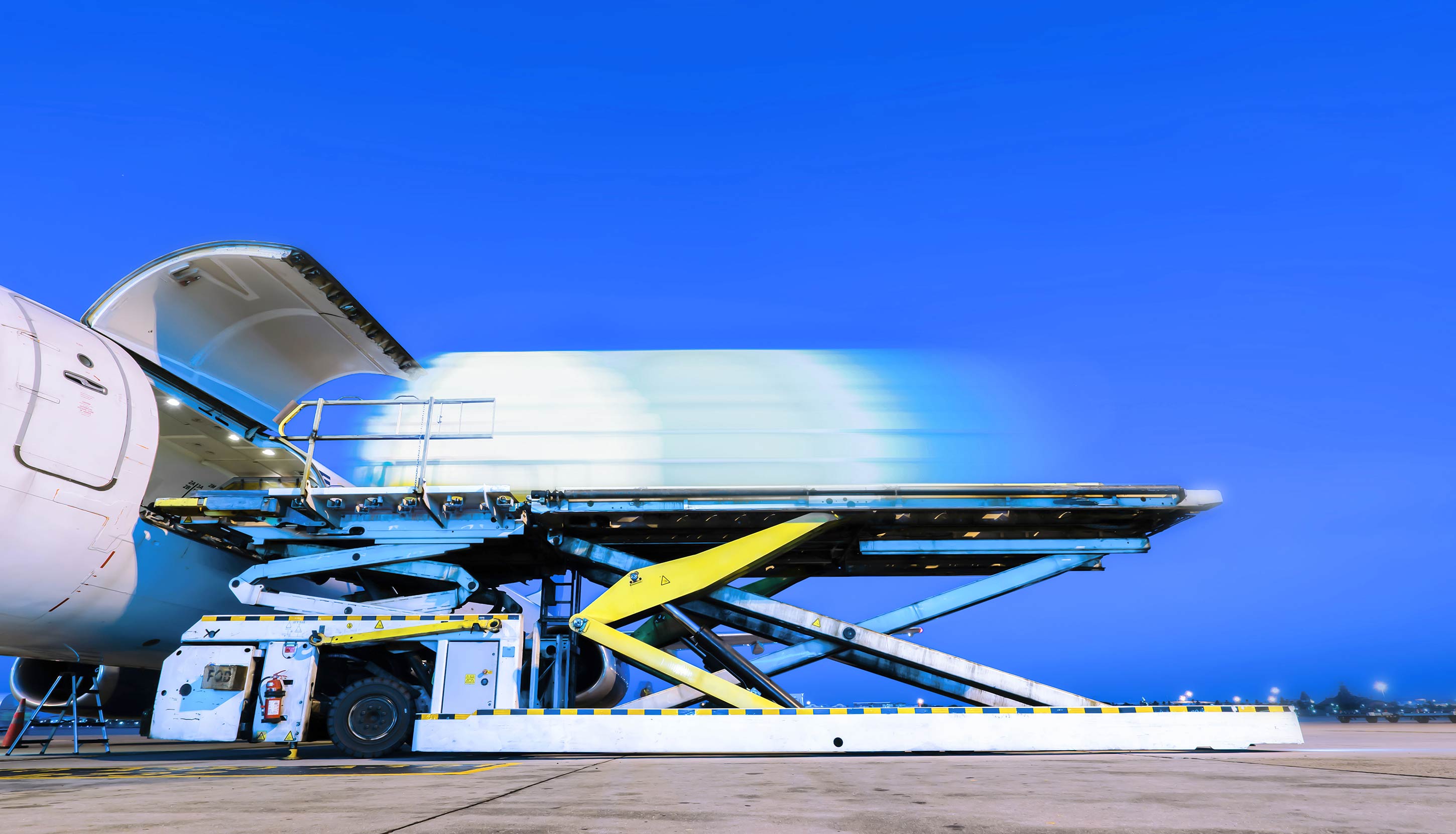A high-tech cargo loader is seen in action, efficiently loading a large container into the cargo hold of an aircraft. The image captures the advanced machinery and logistics involved in modern air freight operations.