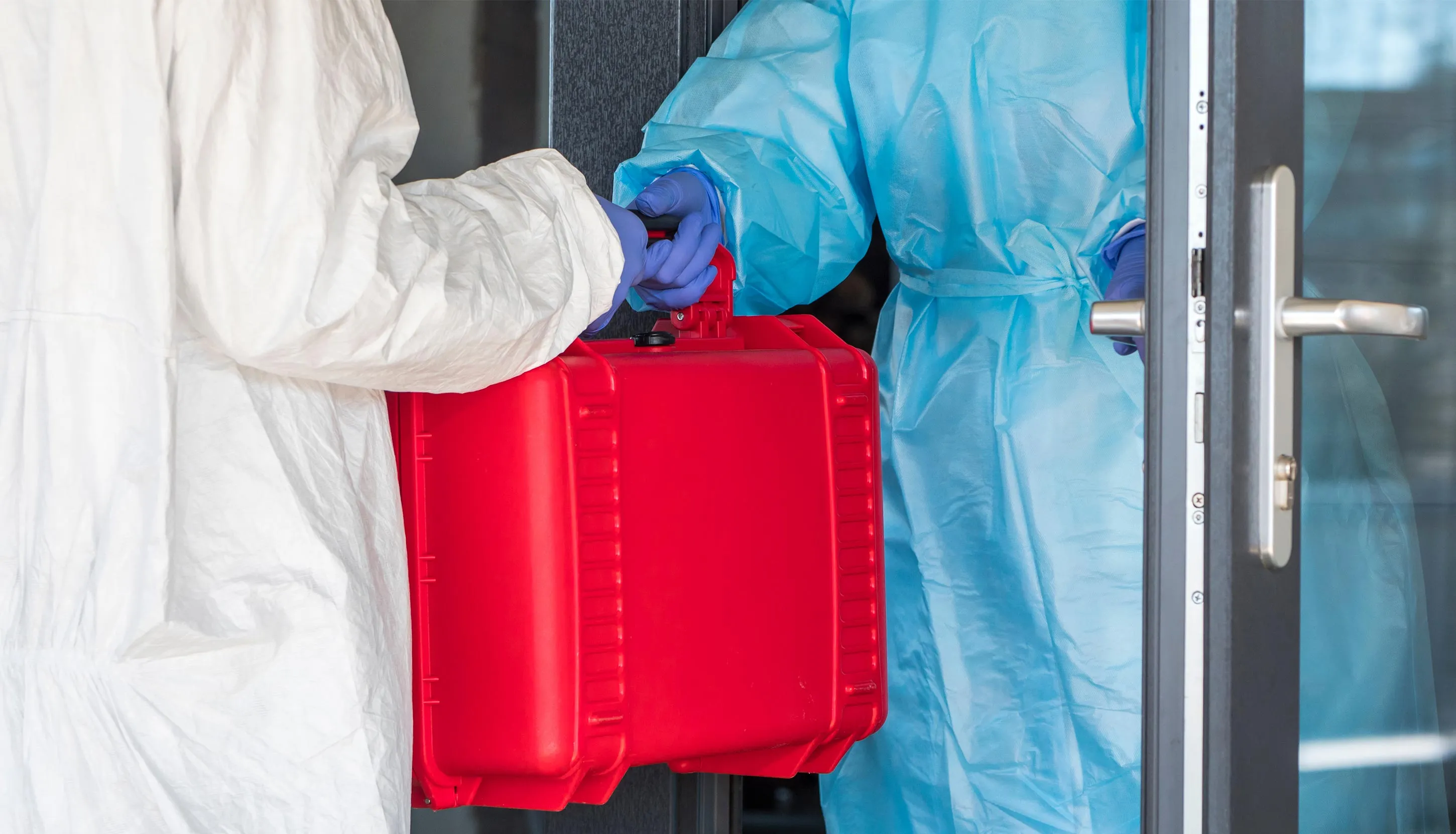 Two people in safety equipment holding a red canister