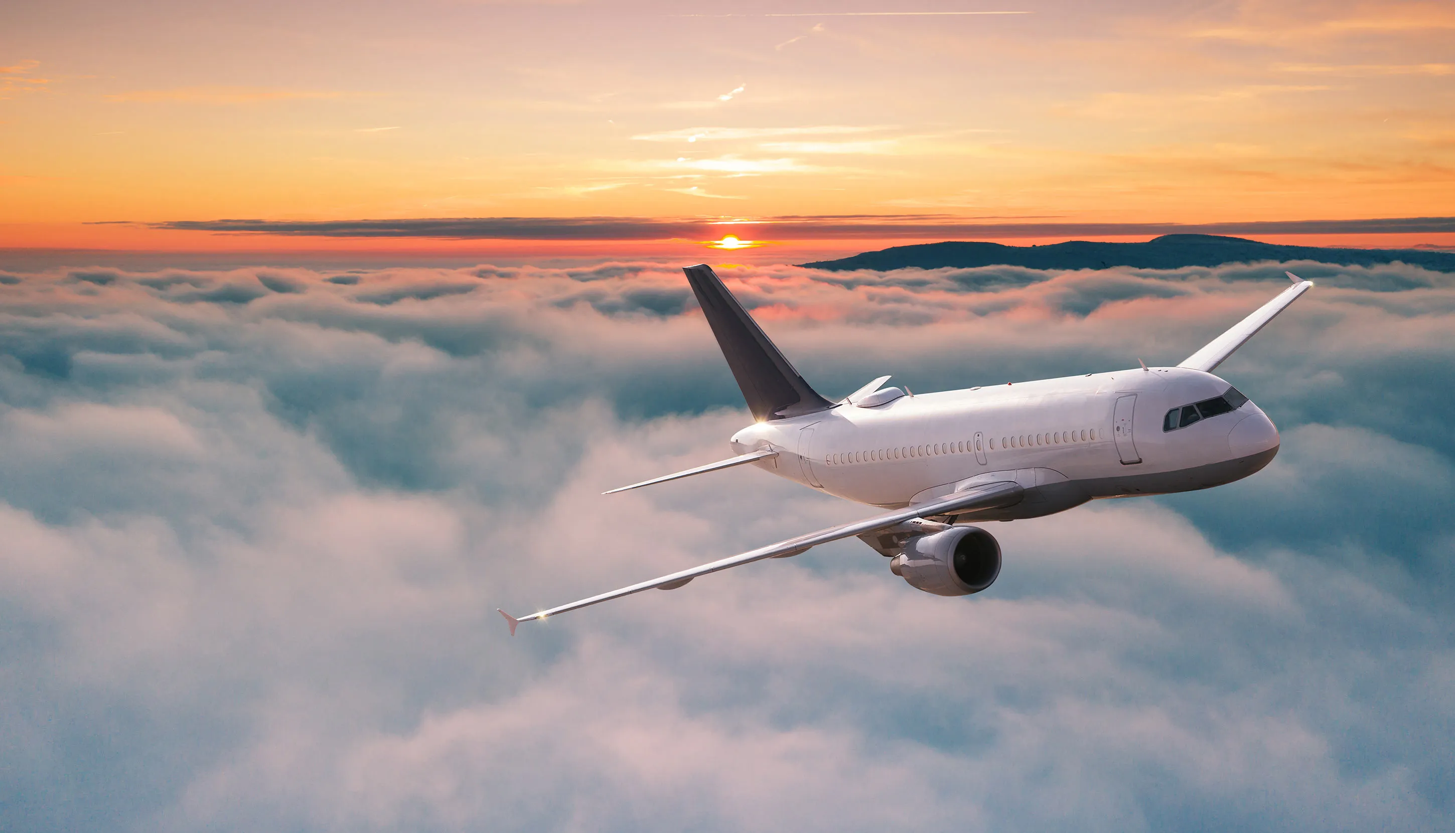 White plane flying above the clouds