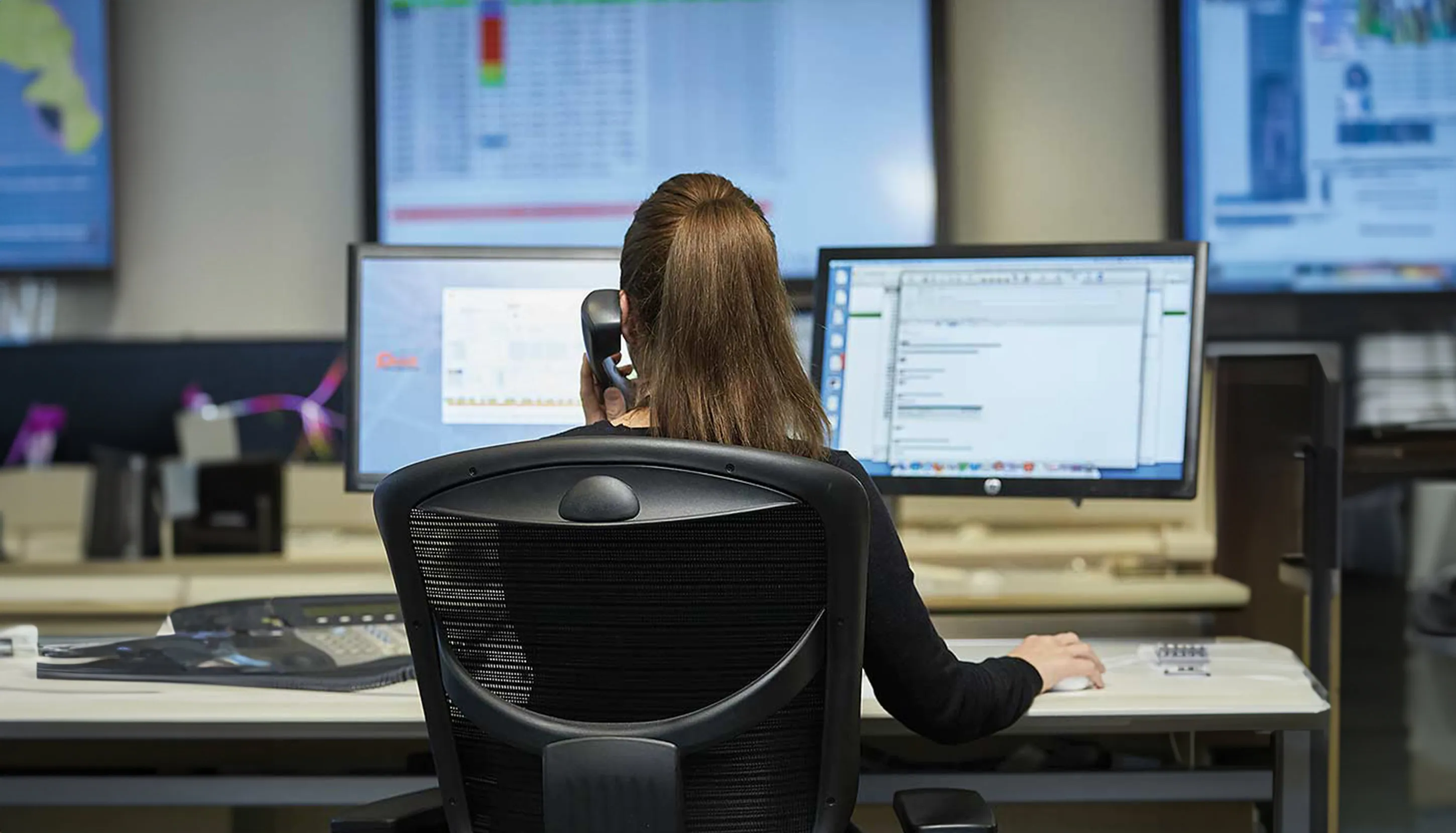 Woman talking on a phone, working on a computer