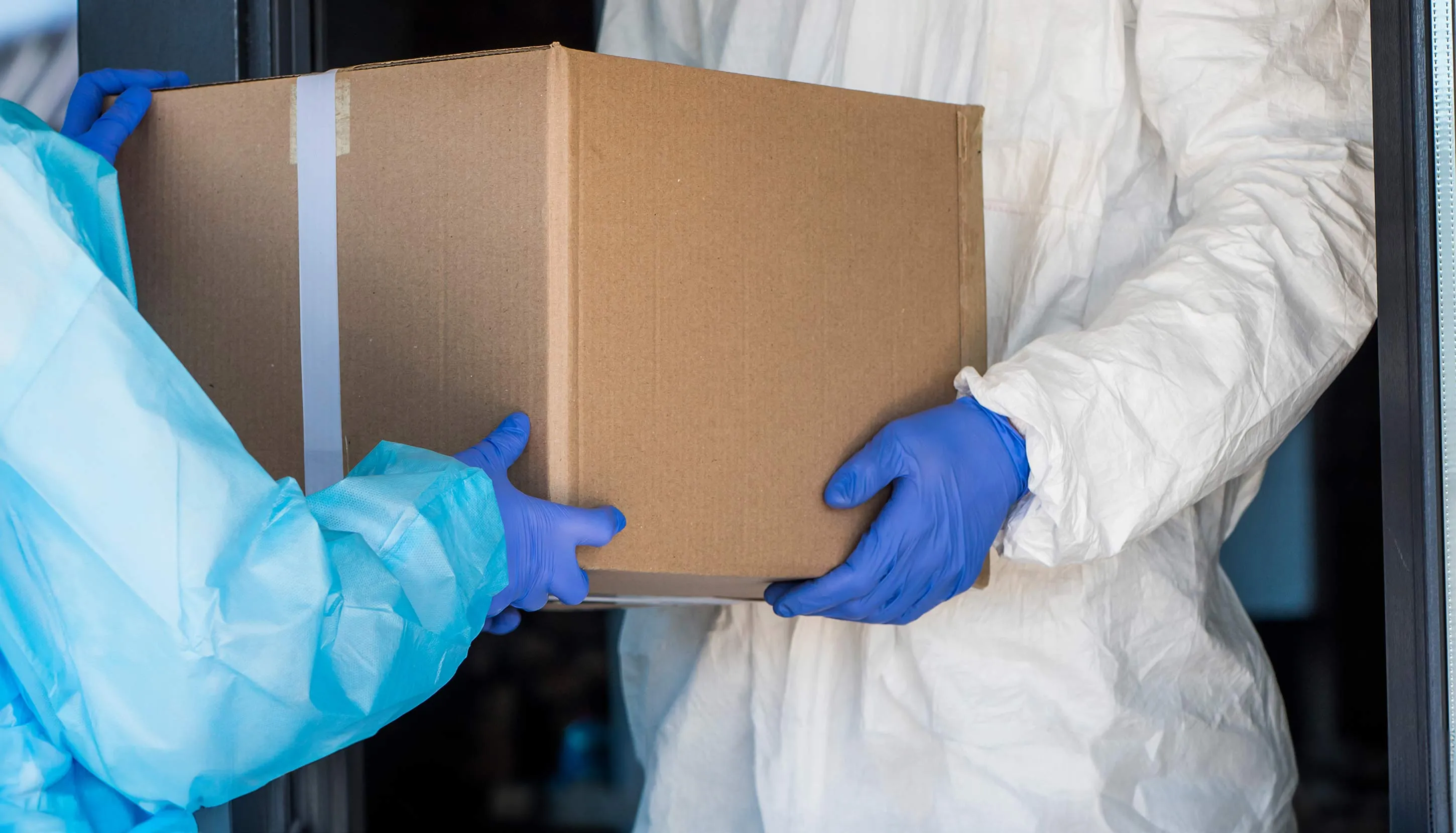 Two workers in protective gear carrying a box