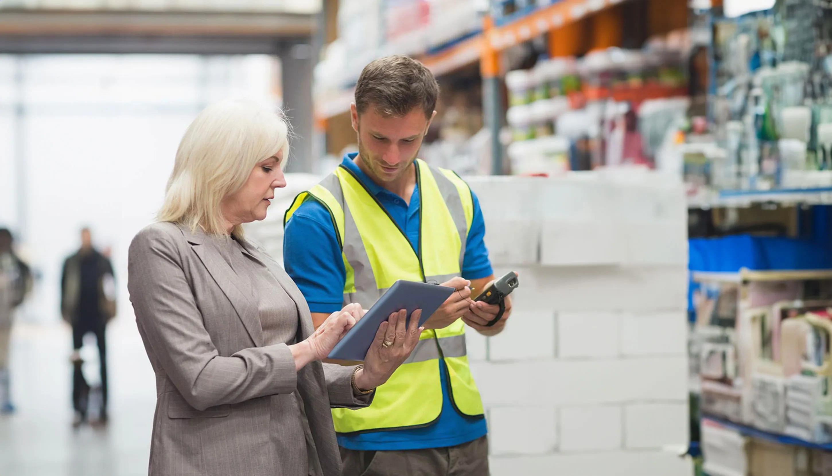 Female boss and a male worker checking something on tablet in a warehouse