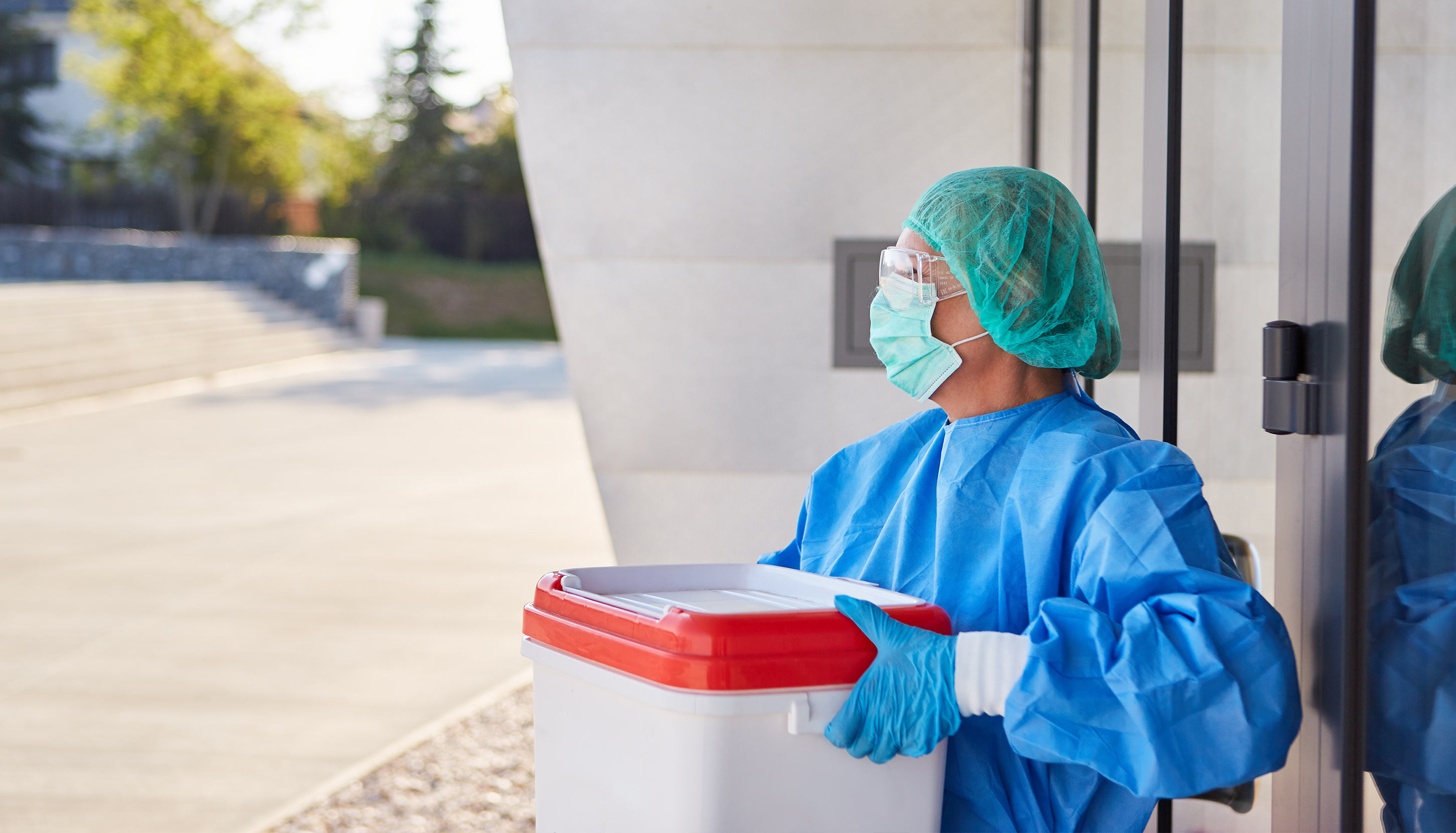 Woman covered in safety medical suit holding a refrigerator box