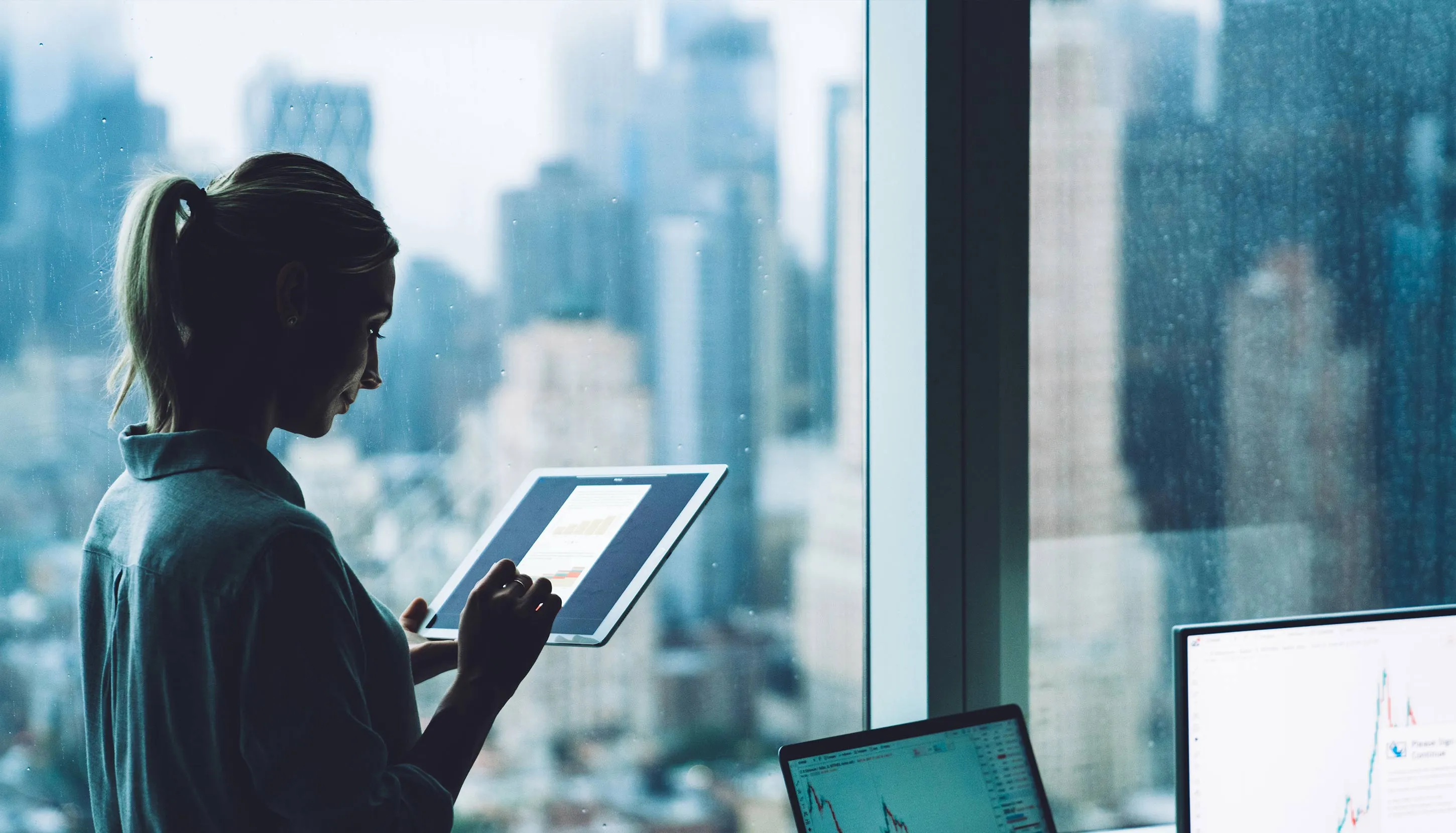 Woman near a big window typing on a tablet