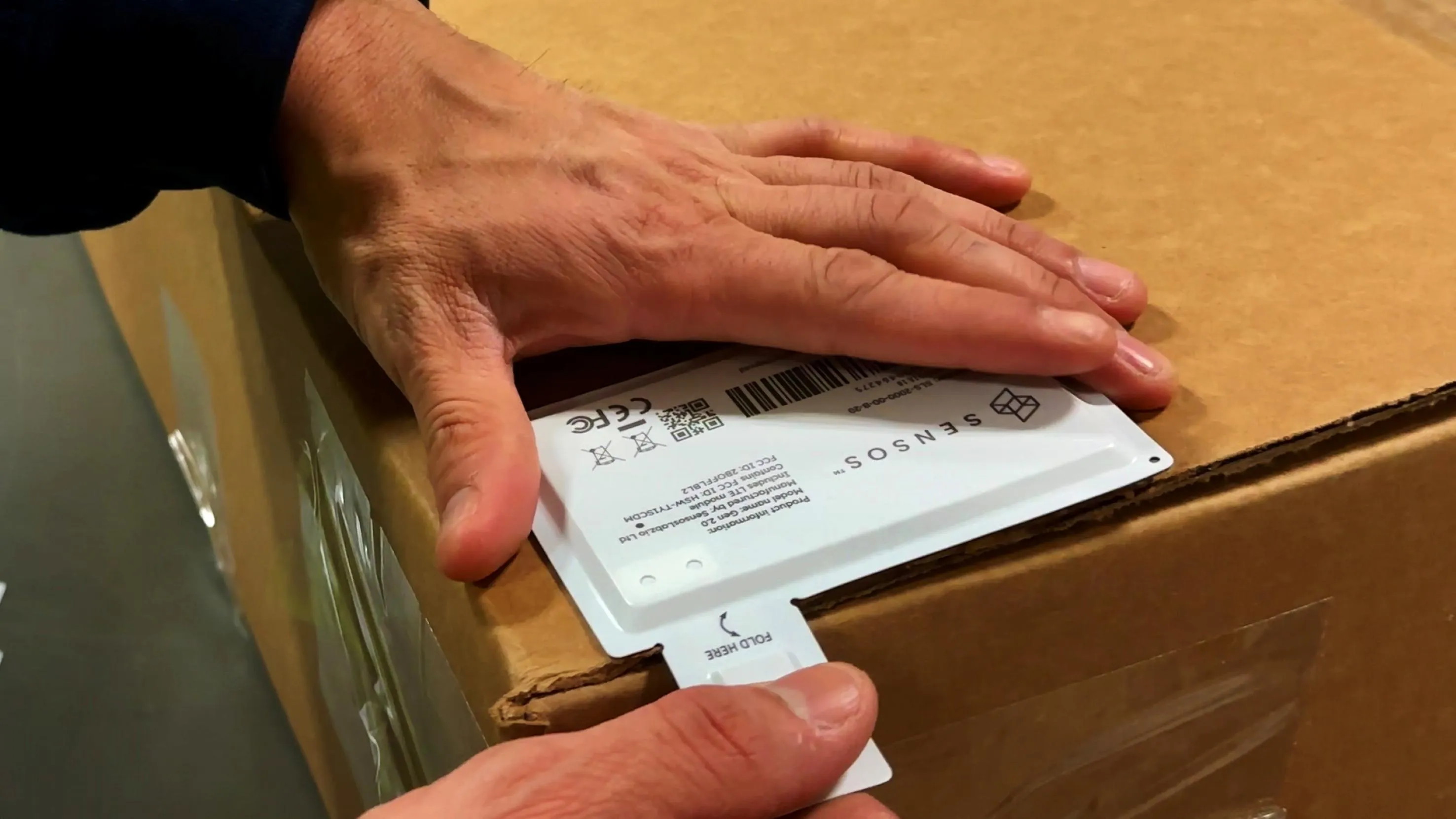 Mens hand sticking a smart label on a package box