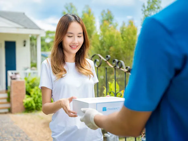 Man hands a package to a woman in front of home